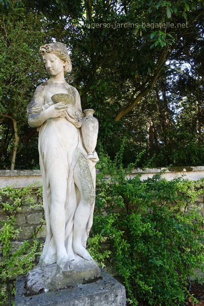 Première statue à gauche représentant une jeune femme tenant une amphore dans la main gauche et un calice. dans la main droite
