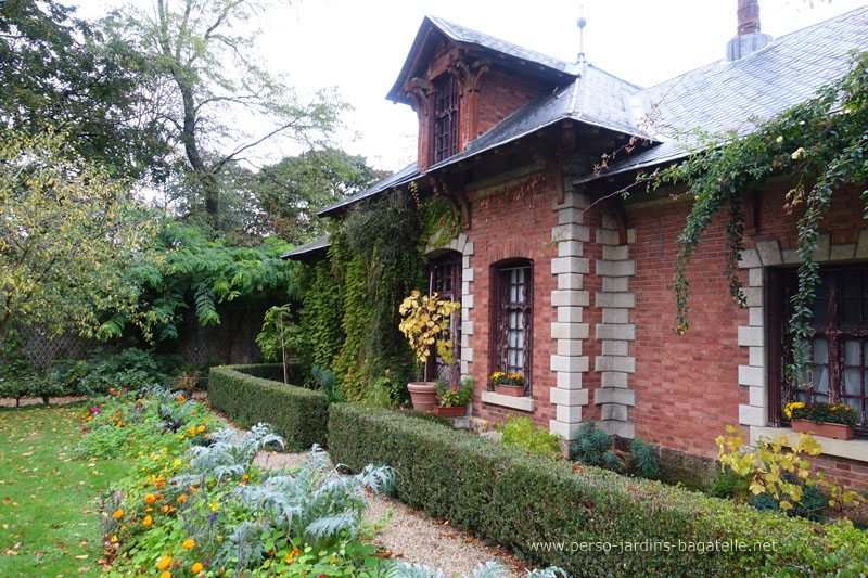 Maison dite du chef jardinier, en brique, entourée de plantes de saison.  Côté face au potager.